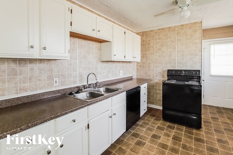 A kitchen with white cabinets and a black stove top oven.