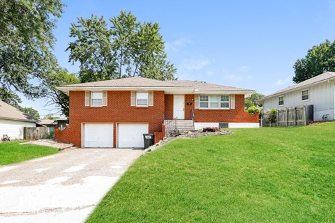 a brick house with a white garage door and a lawn