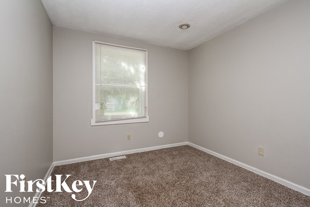 a small room with a carpeted floor and a window