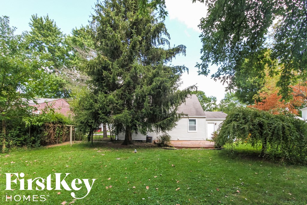 a backyard with a white house and a large tree