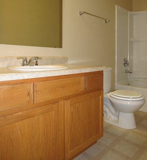A bathroom with a toilet, sink, and wooden cabinets.