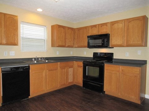 A kitchen with wooden cabinets and black appliances.