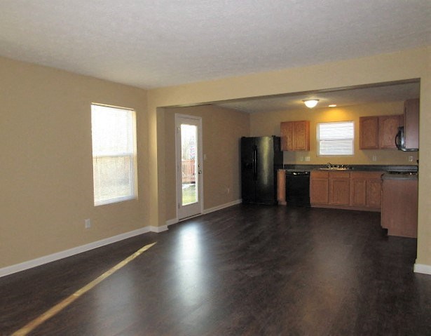 A kitchen with a black fridge and wooden cabinets.