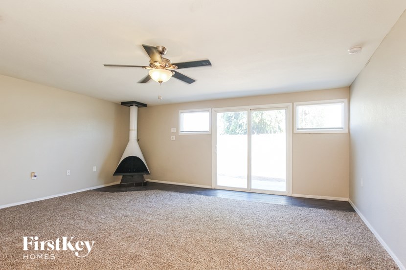 A spacious room with a ceiling fan and a fireplace.