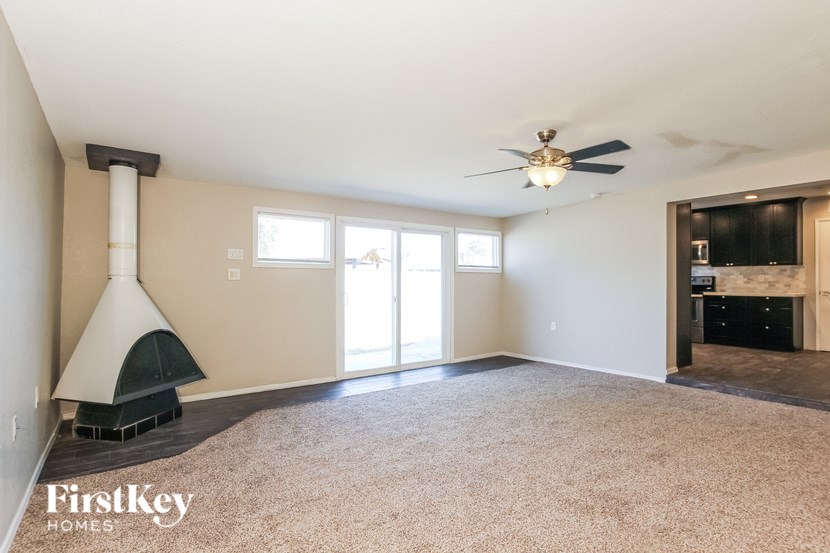 A spacious living room with a fireplace and a ceiling fan.