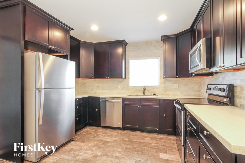 A kitchen with a refrigerator, cabinets, and a stove top oven.