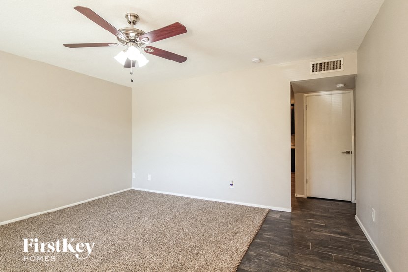 A room with a ceiling fan and a rug on the floor.