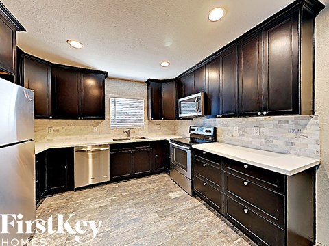 A kitchen with dark wood cabinets and a stainless steel refrigerator.