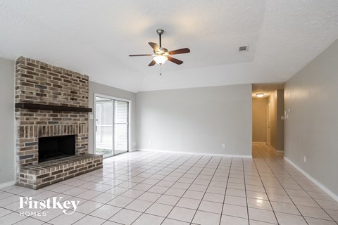 A spacious room with a brick fireplace and a ceiling fan.
