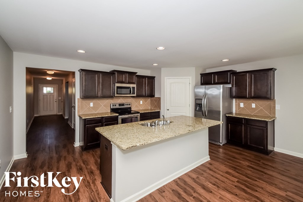 a kitchen with brown cabinets and a marble counter top