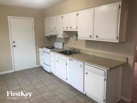 A kitchen with white cabinets and a granite countertop.