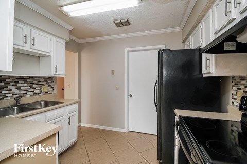 A kitchen with white cabinets and a black fridge.