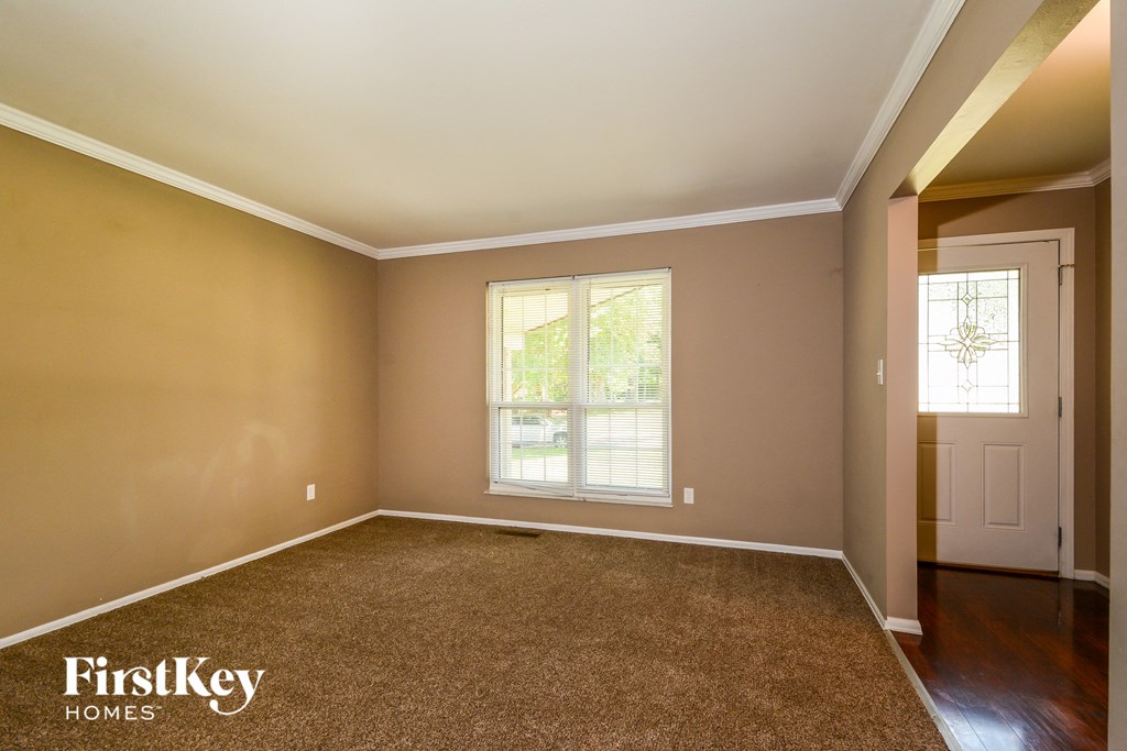 A room with a carpeted floor and a window with blinds.