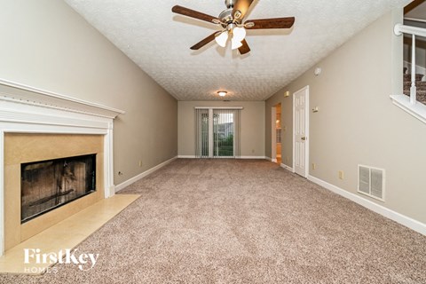 an empty living room with a fireplace and a ceiling fan