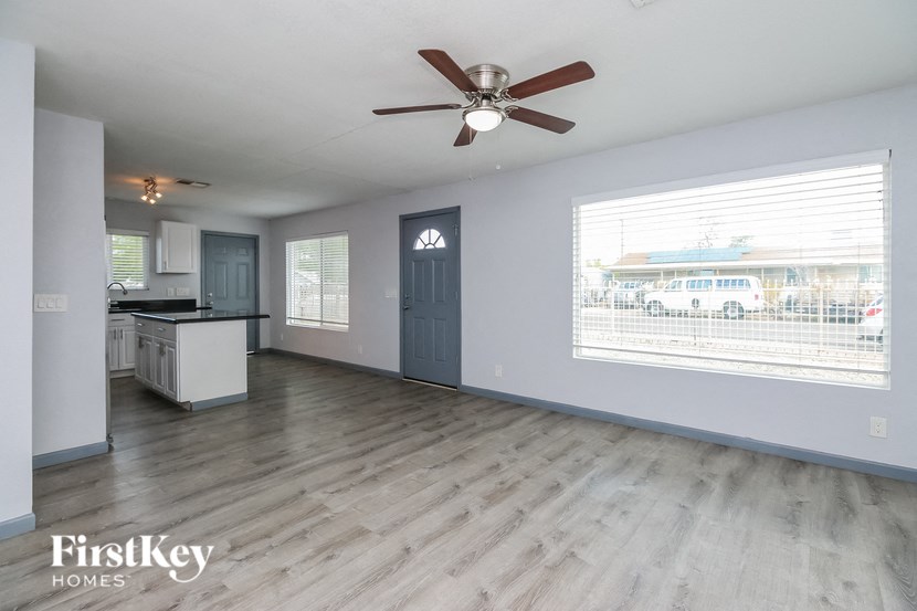 A spacious room with a ceiling fan and a view of the street outside.