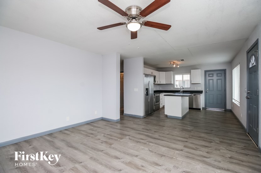 A spacious kitchen with a fan and wooden flooring.