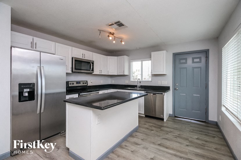 A kitchen with a refrigerator, microwave, and stove top oven.