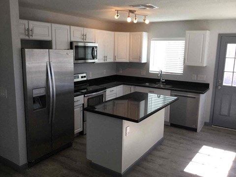 A kitchen with a black countertop and stainless steel appliances.