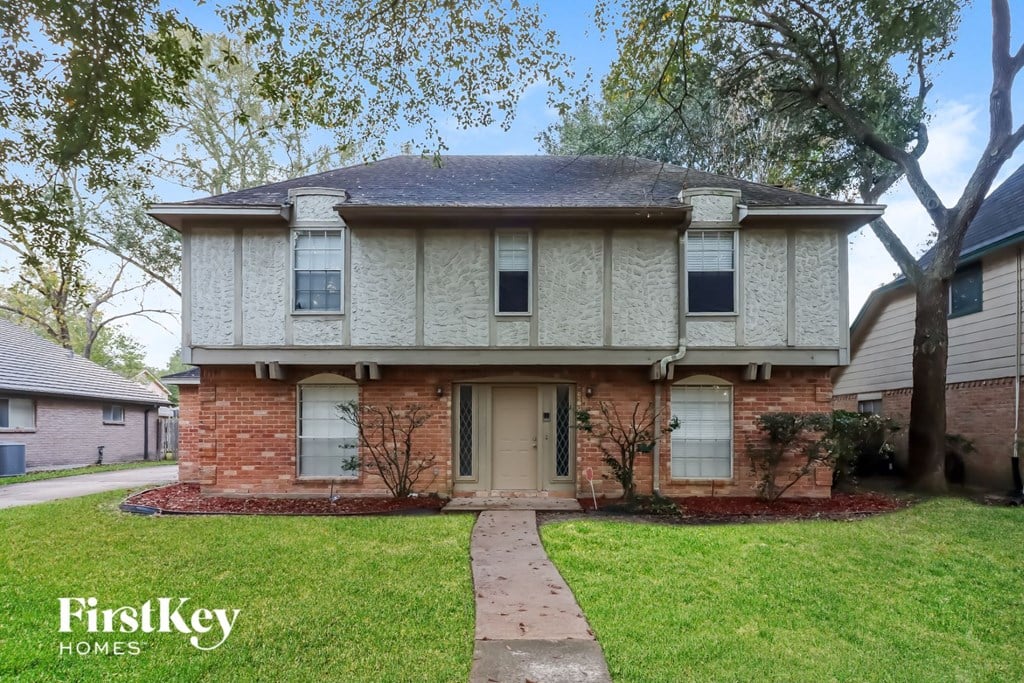 front view of a brick house with white siding and a sidewalk