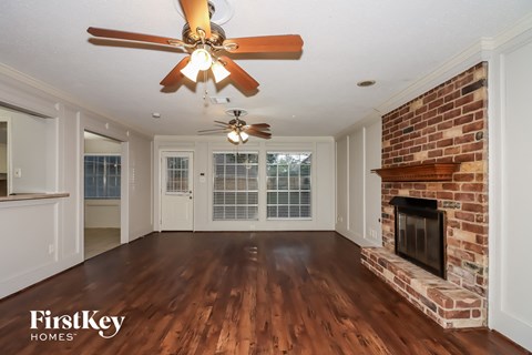 a living room with a brick fireplace and a ceiling fan