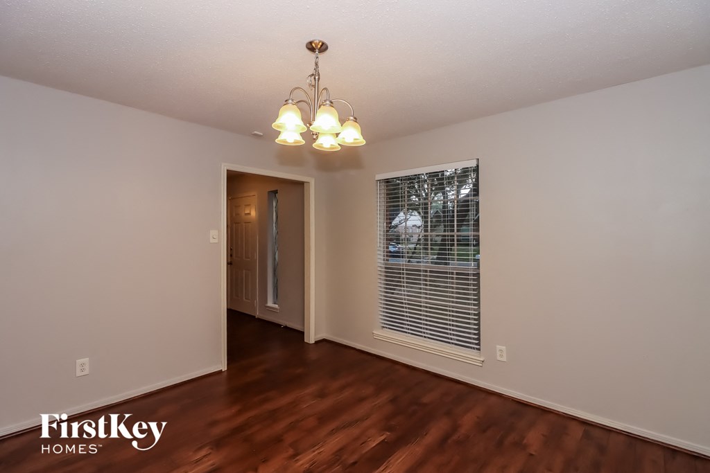 the living room of an empty house with a large window and wooden floors