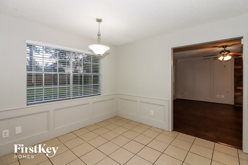 a dining room with a large window and a door to a hallway