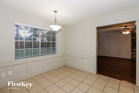 a dining room with a large window and a door to a hallway