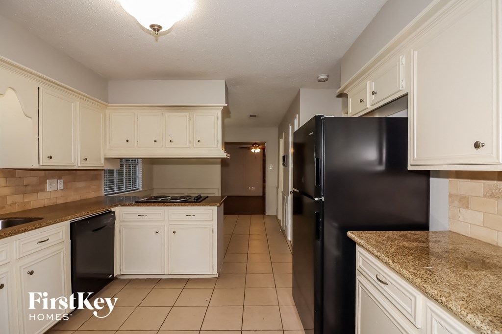 a kitchen with white cabinets and a black refrigerator