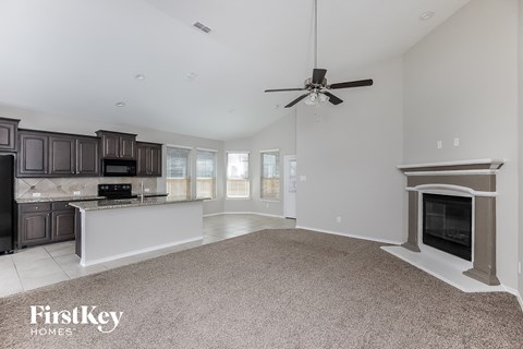 a kitchen and living room with a fireplace and a ceiling fan