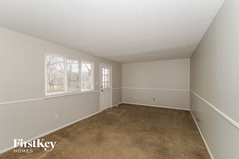 A room with a carpeted floor and a window with trees visible outside.