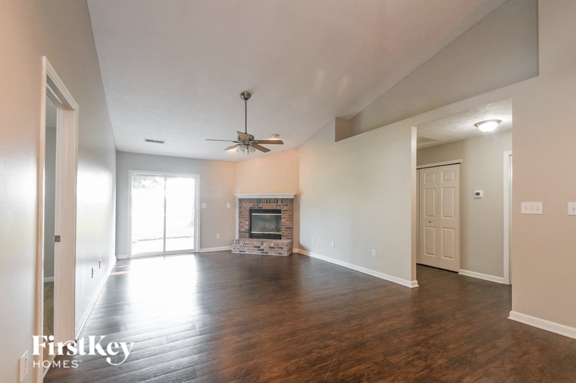 a empty living room with a fireplace and a ceiling fan