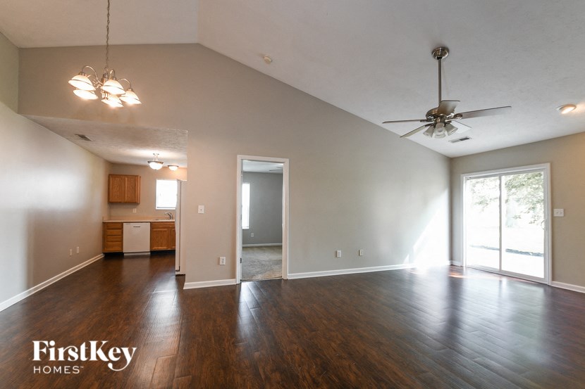 an empty living room with wood flooring and a ceiling fan
