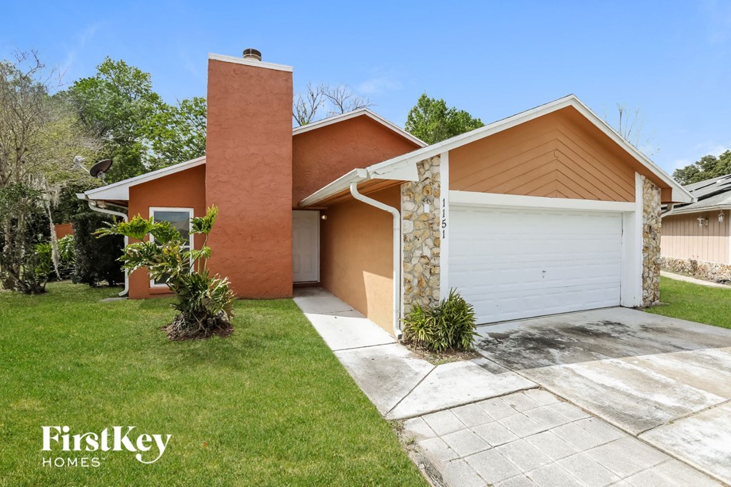 a home with a white garage door and a lawn