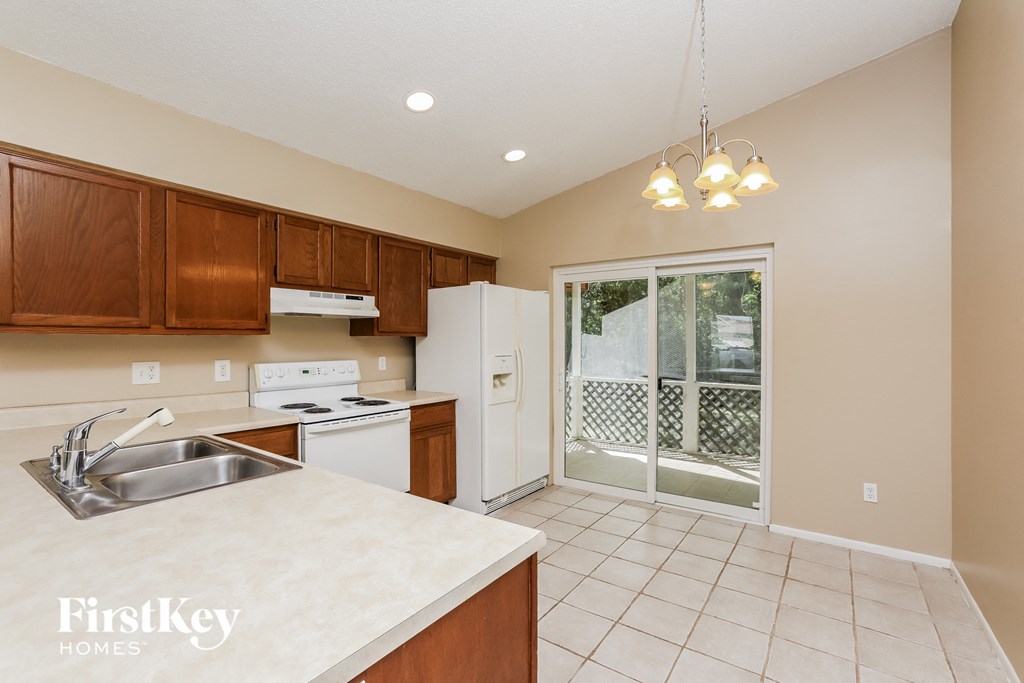 a kitchen with white appliances and wooden cabinets and a door to a balcony