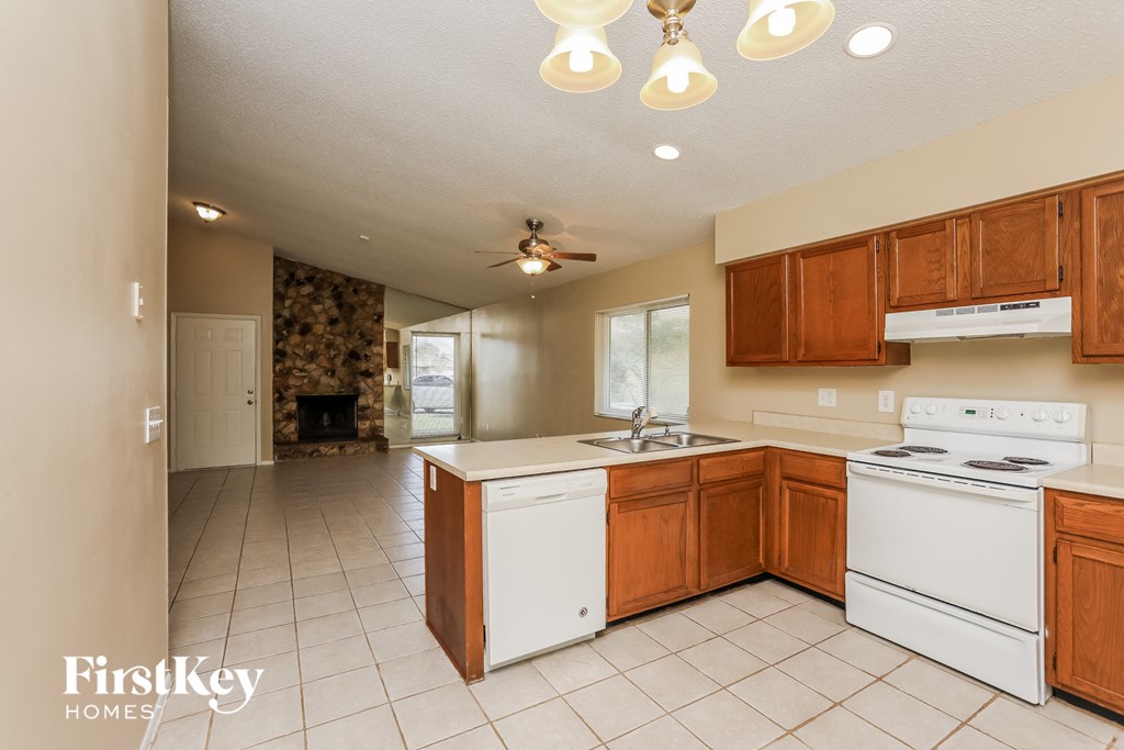 an empty kitchen with white appliances and wooden cabinets