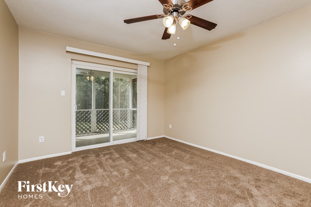 an empty living room with a ceiling fan and a window