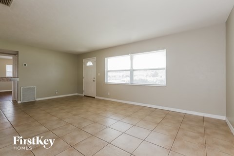 A spacious empty room with tile flooring and a large window.