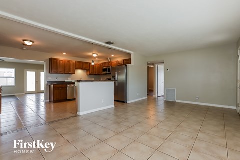 A spacious kitchen with wooden cabinets and a tiled floor.