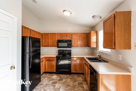 A kitchen with black appliances and wooden cabinets.