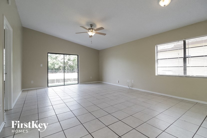 A spacious room with a ceiling fan and sliding glass doors.