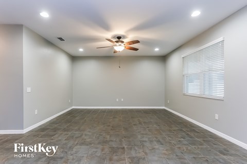 the spacious living room has a ceiling fan and a large window
