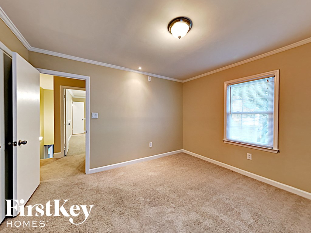 an empty bedroom with a window and a door to the hallway