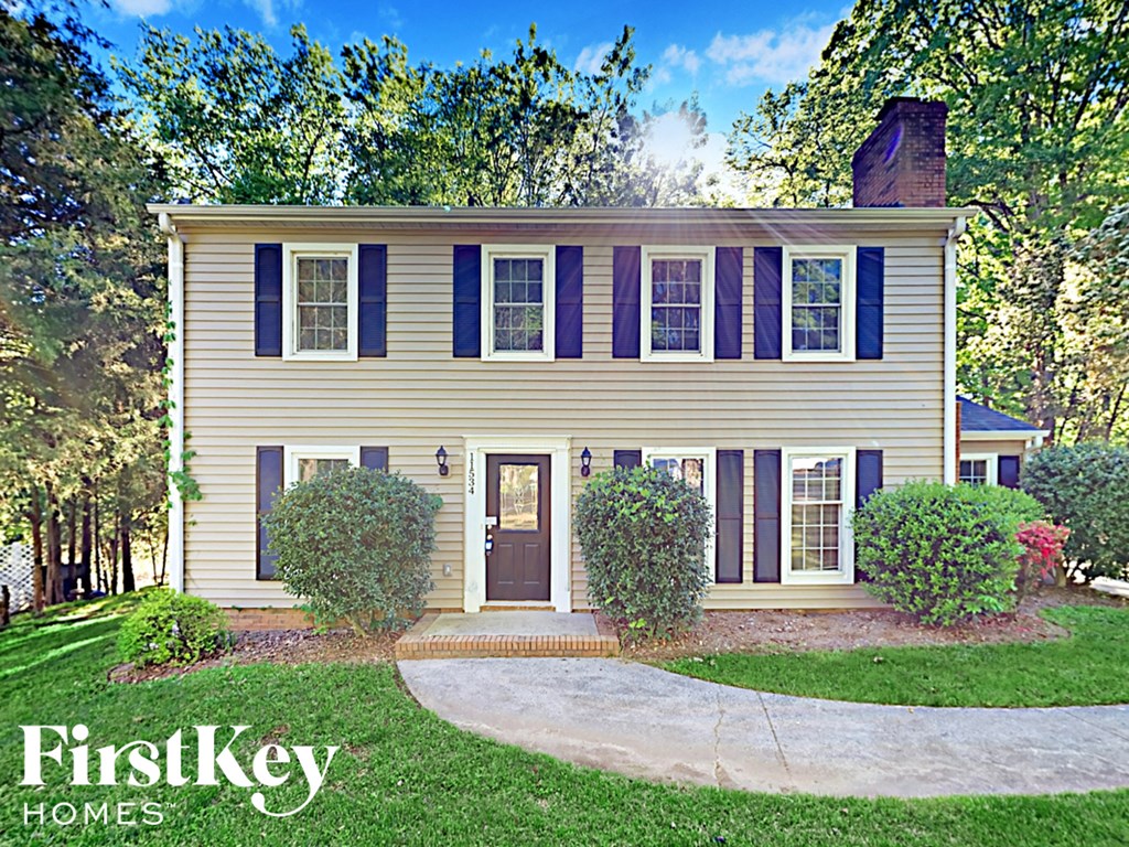 a yellow house with blue shutters and a sidewalk in front