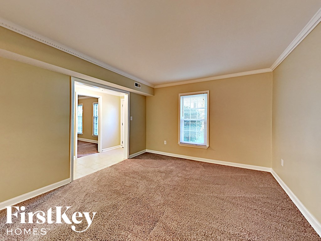 an empty living room with a door to a hallway and a window