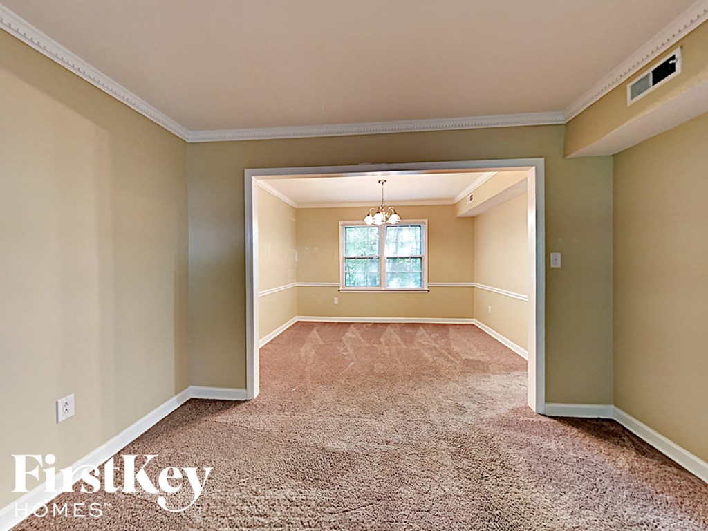 an empty living room with carpet and a chandelier