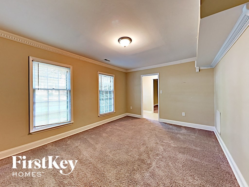 an empty living room with carpet and two windows