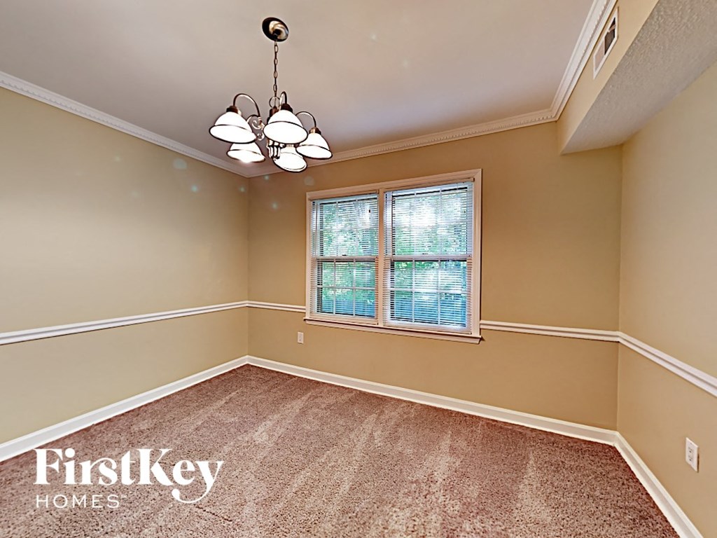 an empty dining room with a window and a chandelier