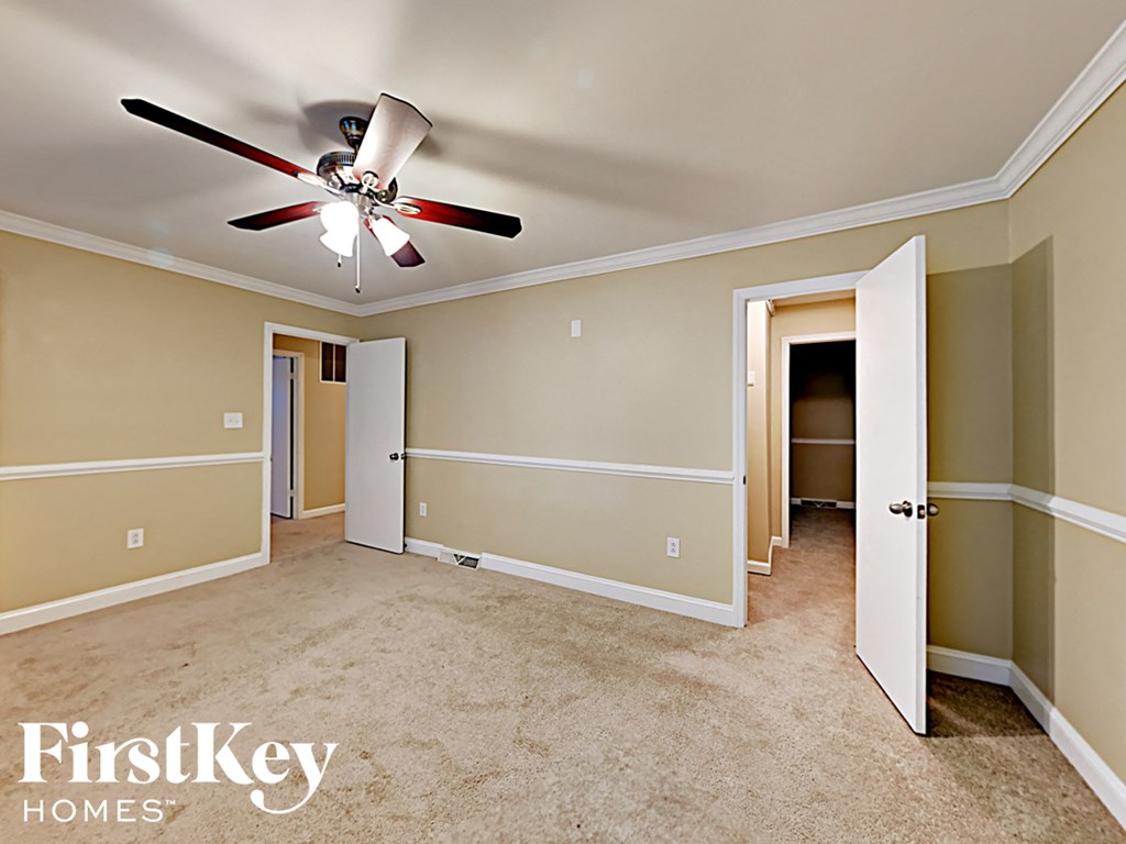 an empty living room with a ceiling fan and a closet