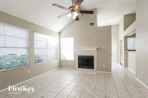 an empty living room with a ceiling fan and a fireplace