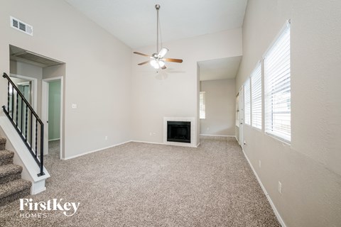 A spacious living room with a fireplace and a ceiling fan.